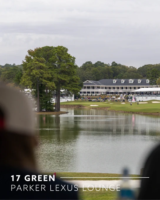 A scenic view of a golf course features a water hazard in the foreground and the 17th green in the background. The Parker Lexus Lounge is visible near the green, with a large building and trees lining the course. Overcast sky above.