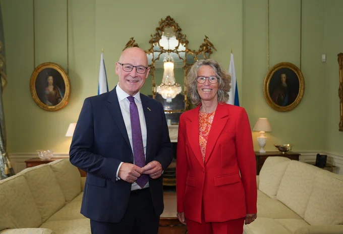 An image of First Minister John Swinney with Susanne Baumann, German Ambassador to the UK, at Bute House. They are smiling at the camera. 