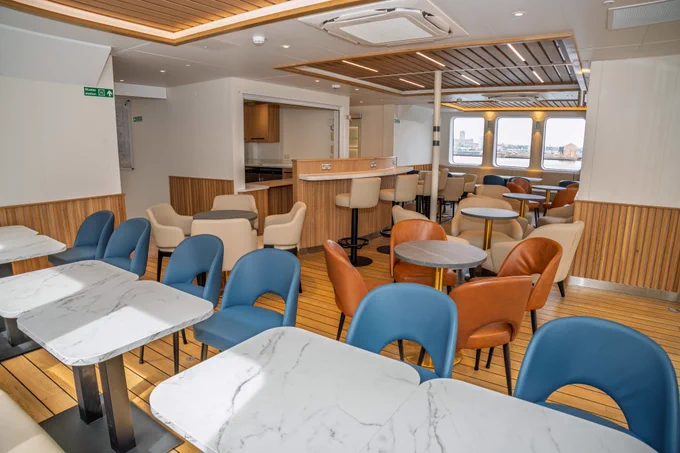 The new ferry will offer a world-class experience, featuring spacious open-plan decks, new seating areas, and vibrant bars where passengers can relax and enjoy stunning views across the River Mersey.