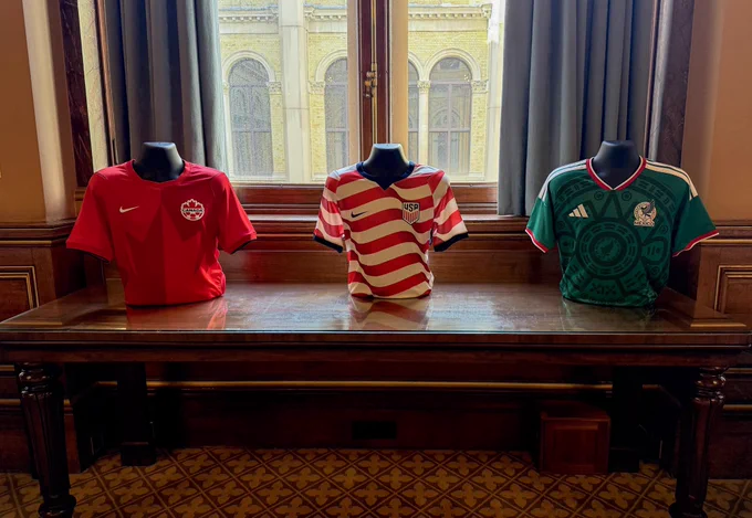 The soccer shirts of Canada, United States, and Mexico teams on display on top of a table at the event.