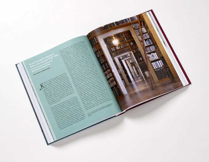 Aufgeschlagenes Buch. Auf der rechten Seite ist ein Bild aus den historischen Räumen der Forschungsbibliothek Gotha zu sehen, auf der linken Seite ein Katalogbeitrag zu Friedrich Jacobs und zur Herzoglichen Bibliothek Gotha.