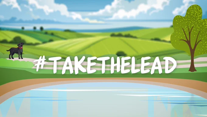 Animated image of pond and rolling hills in the background with black dog on a red lead. The text reads #TakeTheLead.