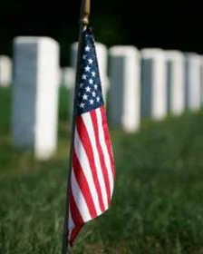Small American flag placed in front of white headstones at a military cemetery