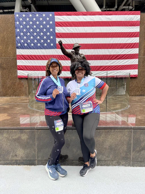 Runners posing with their medals in front of an American flag
