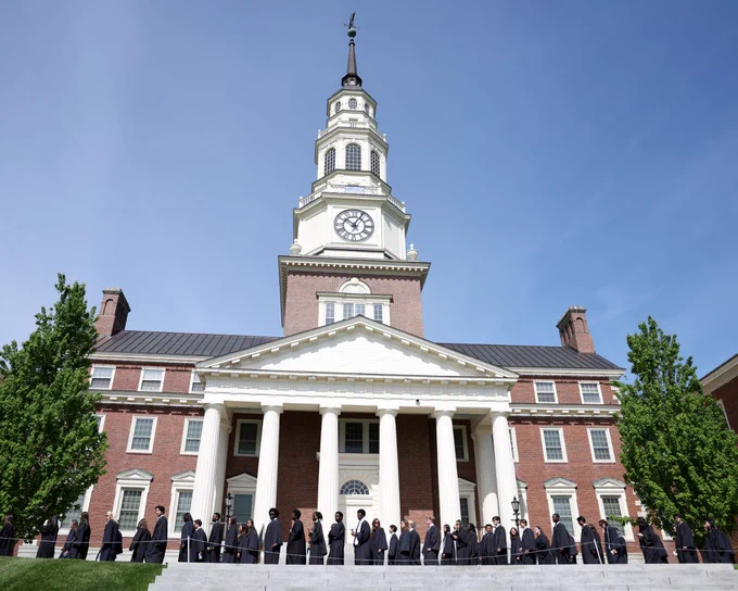 people walking in front of a large building with a clocktower