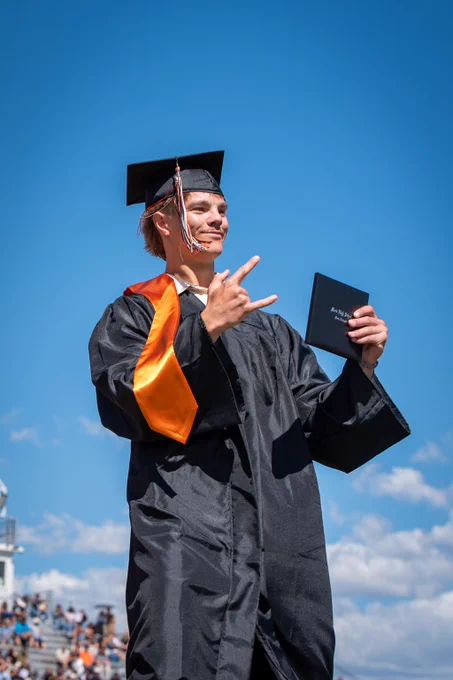 A MHS graduate holds up their diploma.