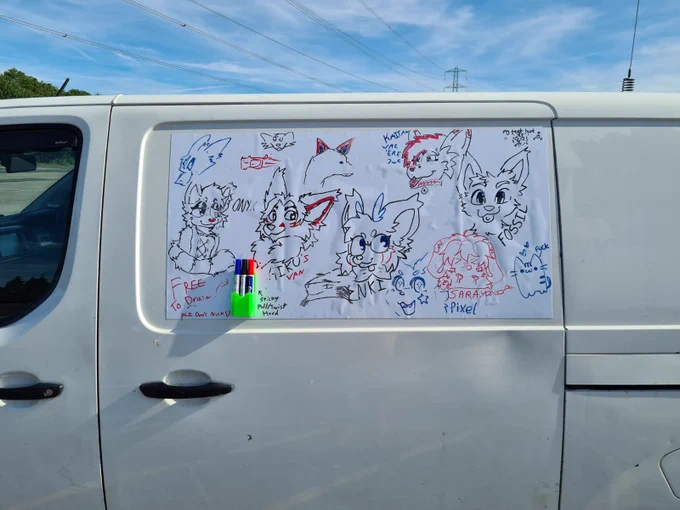 Whiteboard on the side of a van with various furry drawings and signatures