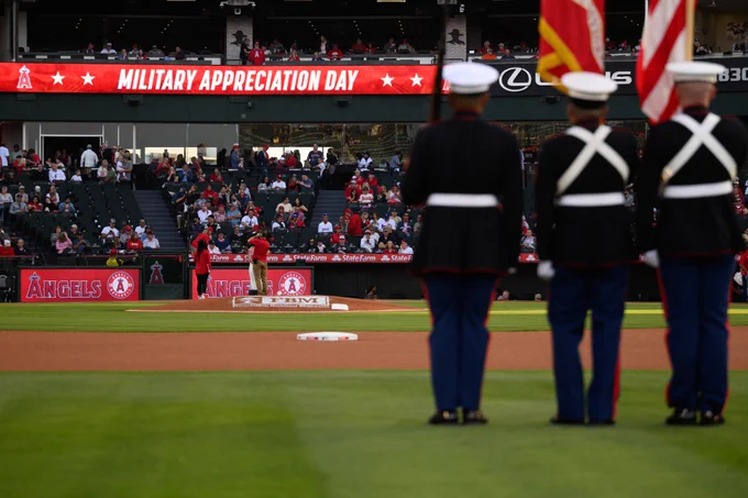Three flag bearers stand at attention before the national anthem with a ribbon banner in the background reading "Military Appreciation Day."