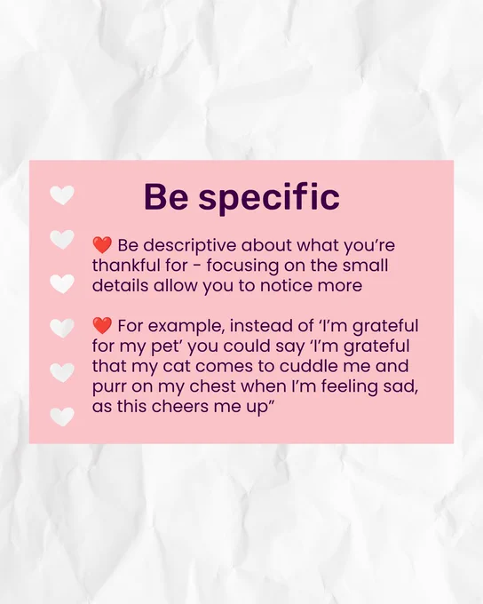 White paper-style background with a pink rectangle that has heart cut-outs down the left side, mimicking hole punches. Dark purple title inside reads 'Be specific'. Text underneath in bullet points reads 'Be descriptive about what you’re thankful for - focusing on the small details allow you to notice more.' 'For example, instead of ‘I’m grateful for my pet’ you could say ‘I’m grateful that my cat comes to cuddle me and purr on my chest when I’m feeling sad, as this cheers me up.”'