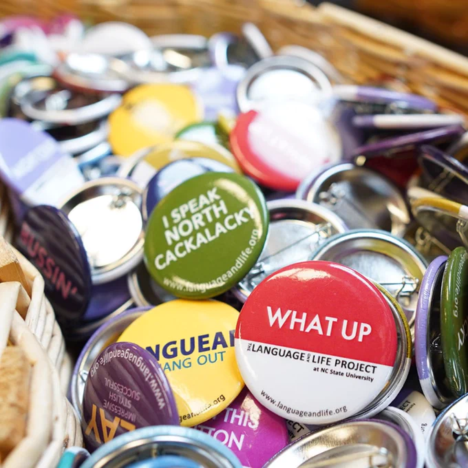 Close-up of colorful pinback buttons promoting language diversity and the Language & Life Project at NC State University.