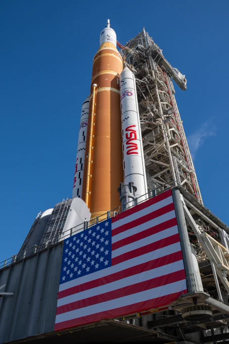 This image shows NASA’s SLS (Space Launch System) and Orion spacecraft for the Artemis II mission at NASA’s Kennedy Space Center. NASA's massive Crawler-Transporter, upgraded for the Artemis program, carried the powerful SLS rocket and Orion spacecraft on the Mobile Launcher from the Vehicle Assembly Building to Launch Pad 39B ahead of the mission. The U.S. flag is prominenet in this image - attached to the base of the mobile launcher. Photographer:NASA/Brandon Hancock
