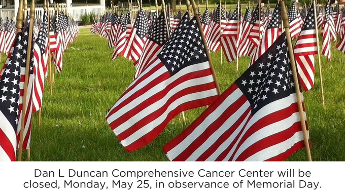 Rows of American flags displayed on a green lawn. A sign reads: "Dan L Duncan Comprehensive Cancer Center will be closed, Monday, May 25, in observance of Memorial Day."