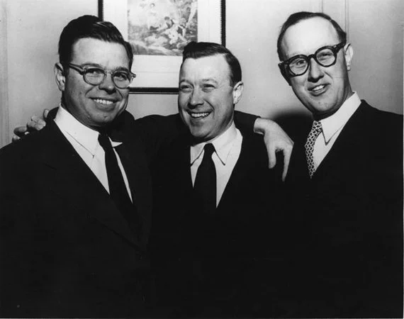 An undated black and white photo of the Reuther brothers with their arms around each other; they are smiling and laughing. Photo courtesy of the Walter P. Reuther Library. 