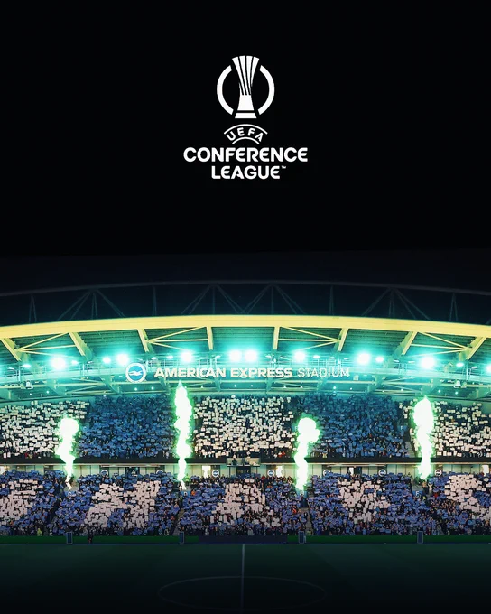 Image of the Amex's east stand with the UEFA Conference League logo in the sky above.