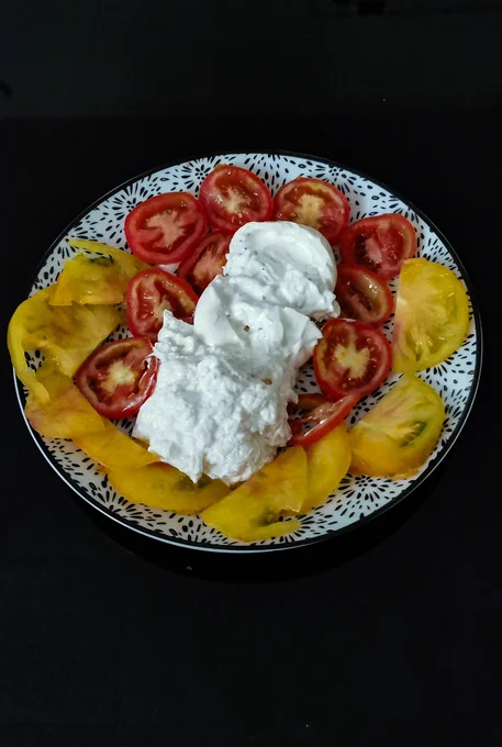 Pascal Saint James enjoying a healthy gourmet starter with red and yellow tomatoes, burrata and stracciatella, reflecting balanced eating, Mediterranean lifestyle and vitality after 60.