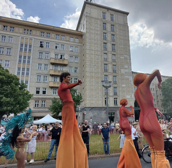 Rot-orange gekleidete Tänzer auf Stelzen.
