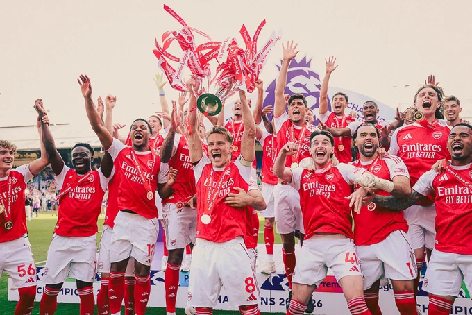 Martin Odegaard lifts the Premier League trophy as Arsenal captain, surrounded by the squad celebrating 