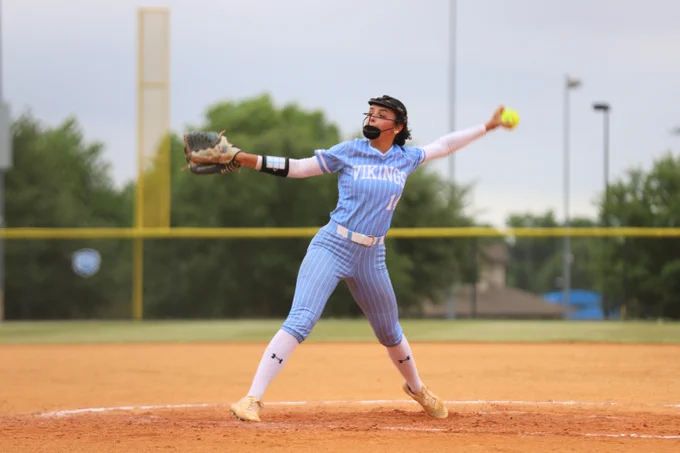 Softball player in a blue Vikings uniform about to pitch the ball.
