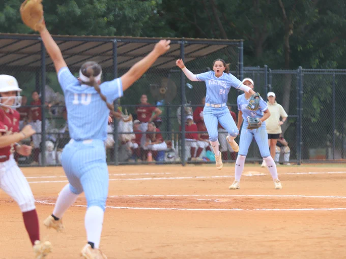 Softball players in light blue uniforms celebrate on the field.