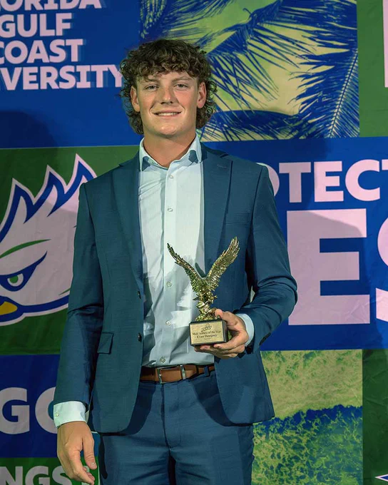 a photo of Evan Dempsey holding a trophy at an event