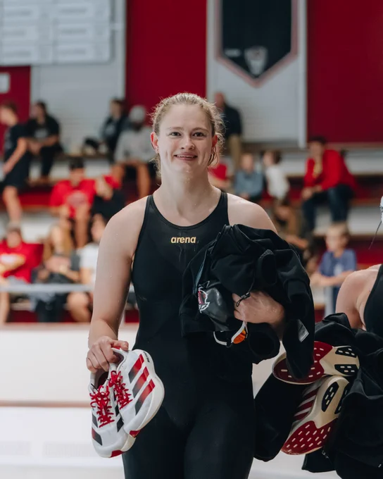 Image of Eneli Jefimova post race carrying clothes and smiling.
