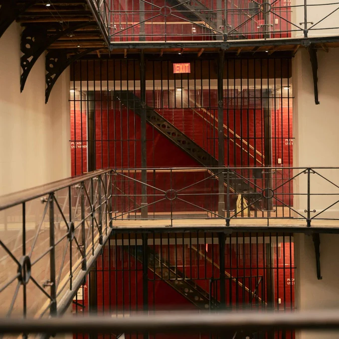 Interior view of a multi-level building with black metal railings and staircases against red walls.