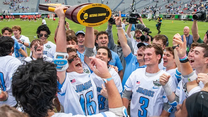 Senior Ben Clarke holds the NCAA trophy while teammates celebrate around him NCAA following their victory on May 24, 2026. Photo: Stephen Blue/Sideline Media