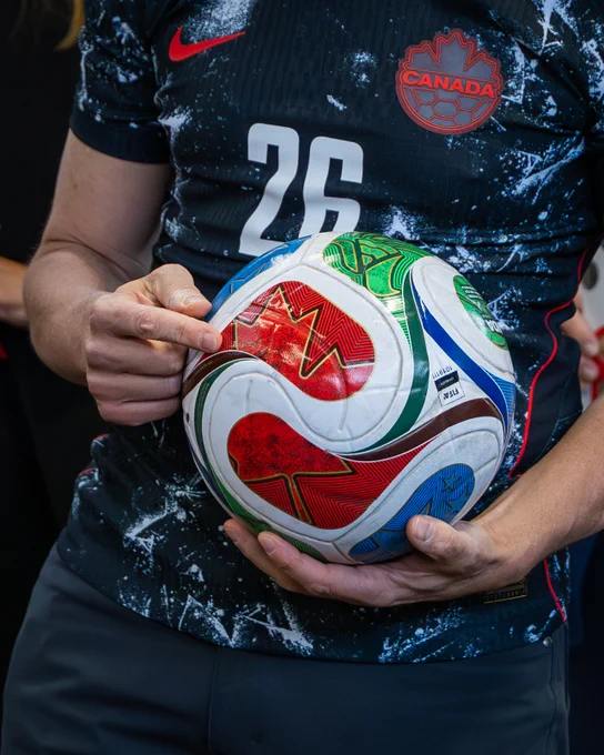 Prime Minister Mark Carney points to a red maple leaf on the FIFA World Cup soccer ball during a FIFA World Cup 26™ event in Ottawa. 
