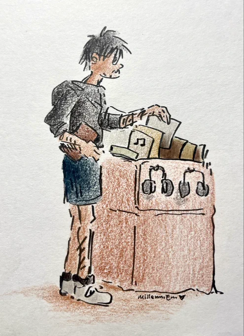 Olruggio wears a black hoodie and blue gym shorts and white sneakers. He holds a book under one arm and looks through a shelf of records with the other. Paris of headphones hang on the shelf.