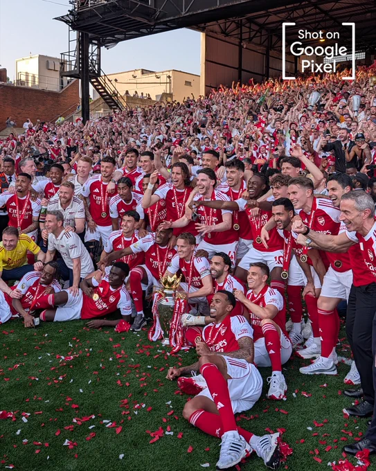 A group photo of the Arsenal squad around the Premier League trophy