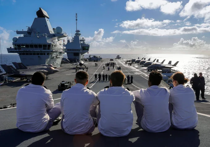 Personnel atop a ship in sunny weather.