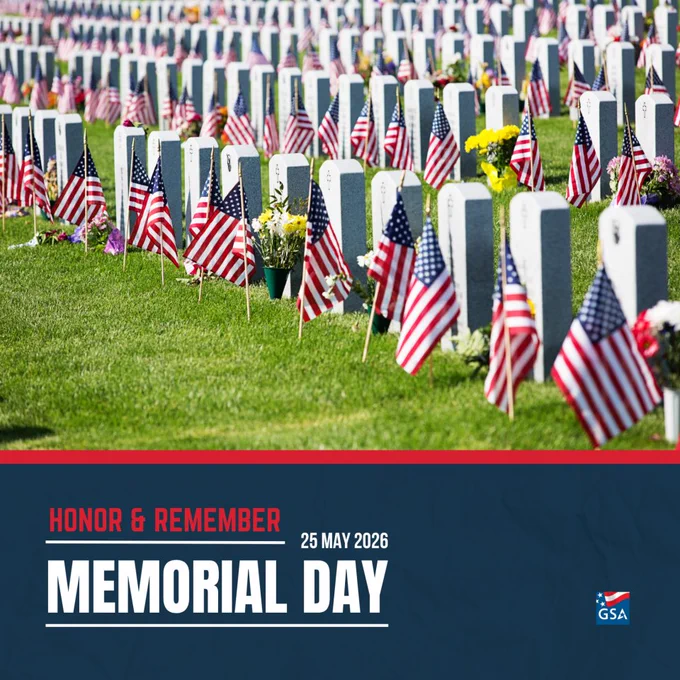 Rows of white gravestones adorned with American flags and flowers in a military cemetery on Memorial Day.