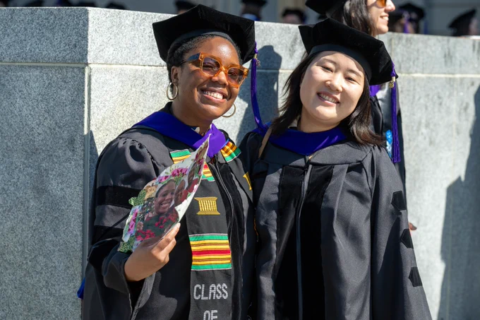 Two graduating students, smiling outdoors