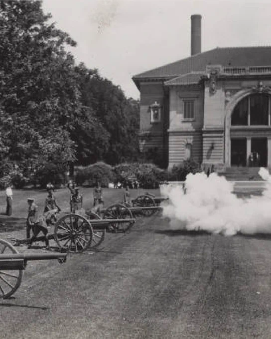 Black and white photo of military personnel and cannons with smoke in front of Eliza Fowler Hall 