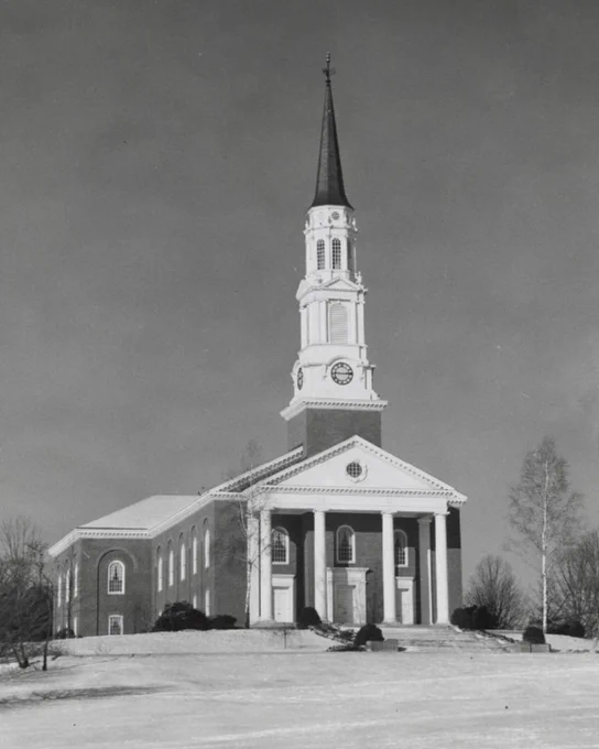 An old, black & white photo of the Memorial Chapel, underneath a vast sky and surrounded by a few trees