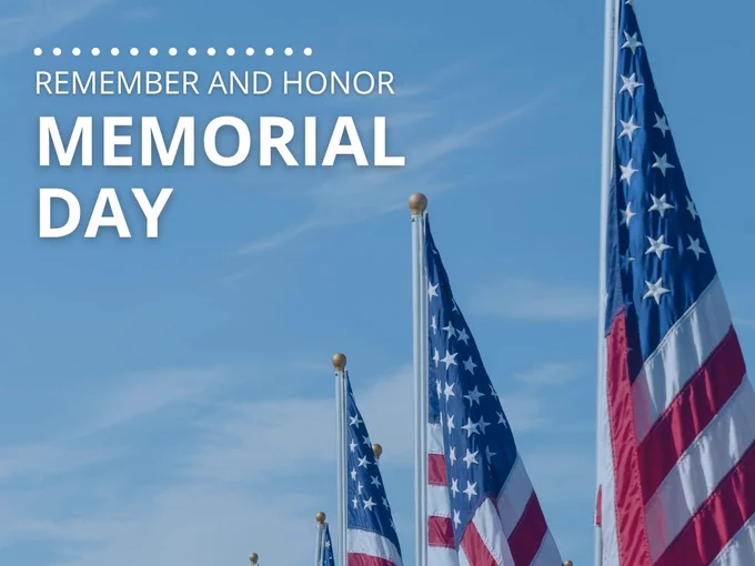 Multiple American flags waving under a clear blue sky with Memorial Day remembrance text.