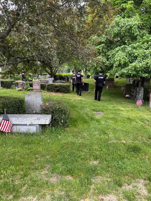 Student officers walking  in a cemetery adorned with American flags.