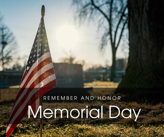 American flag placed at a gravesite with sunlight in the background, with text reading Remember and Honor Memorial Day.