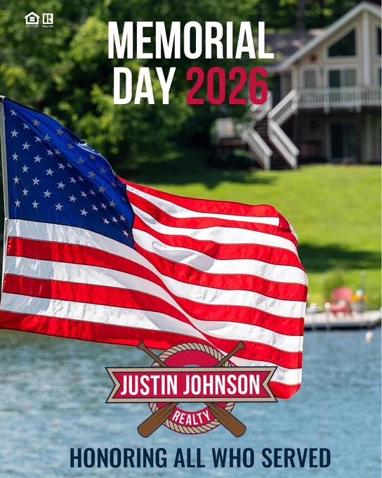 An American flag waves in front of a lakeside house, promoting Memorial Day 2026 by Justin Johnson Realty. The text honors those who served.