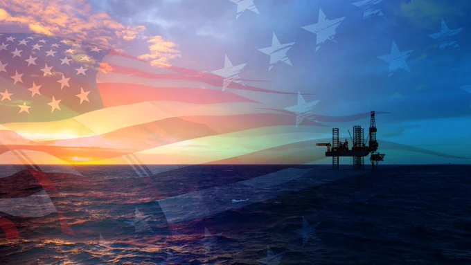 An American flag is superimposed over an oil platform in the ocean with the sun setting in the background. 