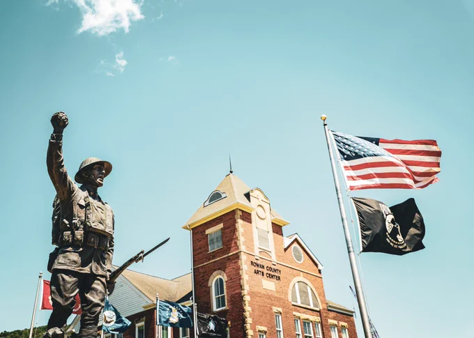 A "Spirit of the American Doughboy" monument and several flags with the U.S. flag being the most prominent are located in front of the Rowan County Arts Center building