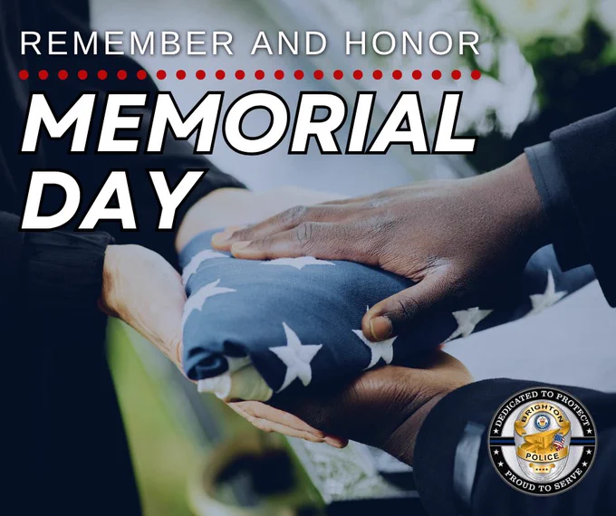 Two hands respectfully holding a folded American flag during a Memorial Day tribute with a police badge emblem in the corner.