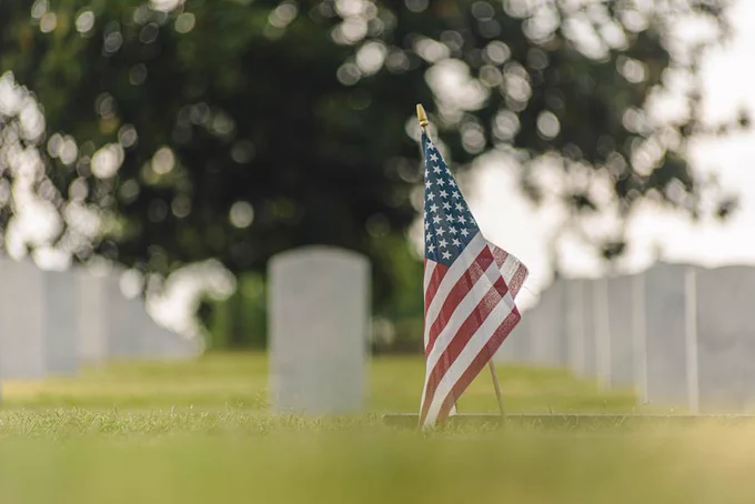 American flag at a Chattanooga cemetery with headstones in blurred background.