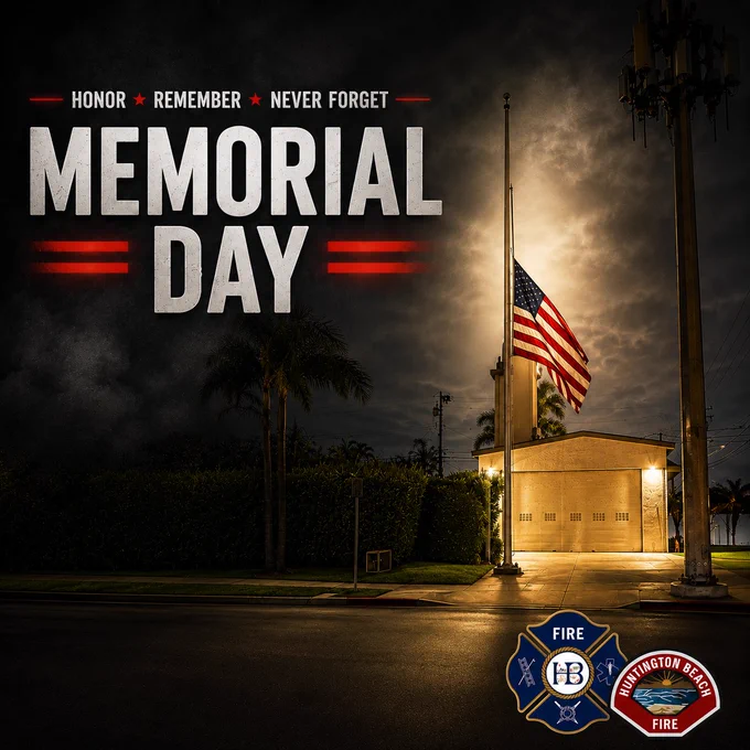 Memorial Day tribute graphic featuring Huntington Beach Fire Department Station 3 at night with an American flag displayed at half staff in front of the station. Large text reads “Honor Remember Never Forget” above “Memorial Day.” The station is illuminated with warm lighting beneath a dark cloudy sky, with a spotlight effect highlighting the flag. Huntington Beach Fire Department logos appear in the lower right corner.