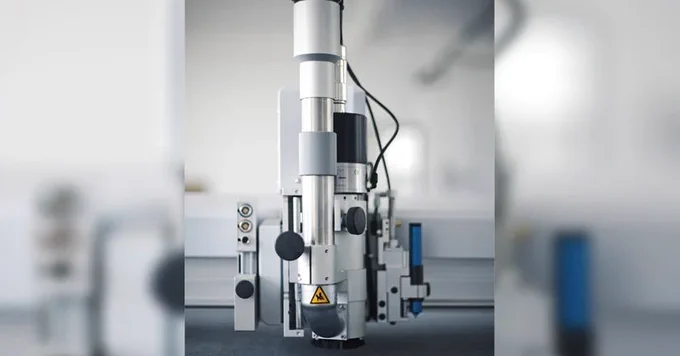 Close-up of a silver industrial tool head mounted on a machine gantry.