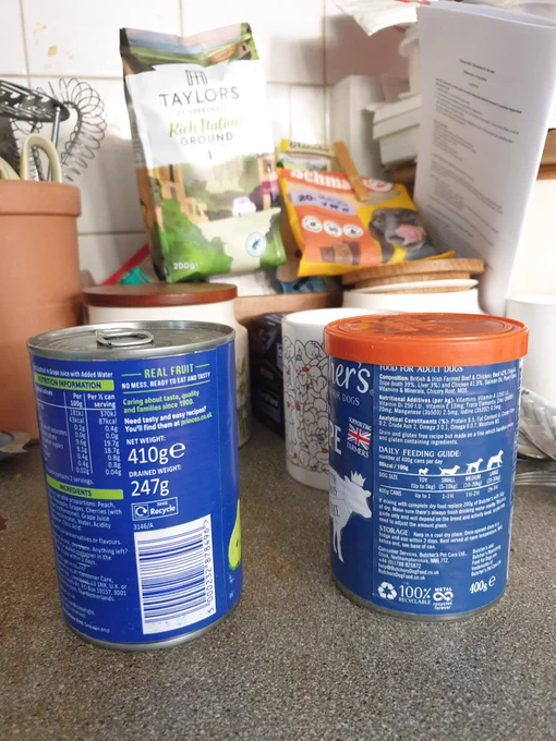 Two similar tins with blue labels on the kitchen worktop.