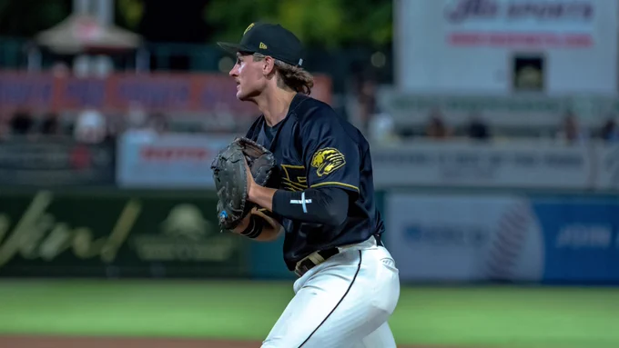 Tanner Thach runs with his mitt while wearing a black Fresno Grizzlies jersey and white pants