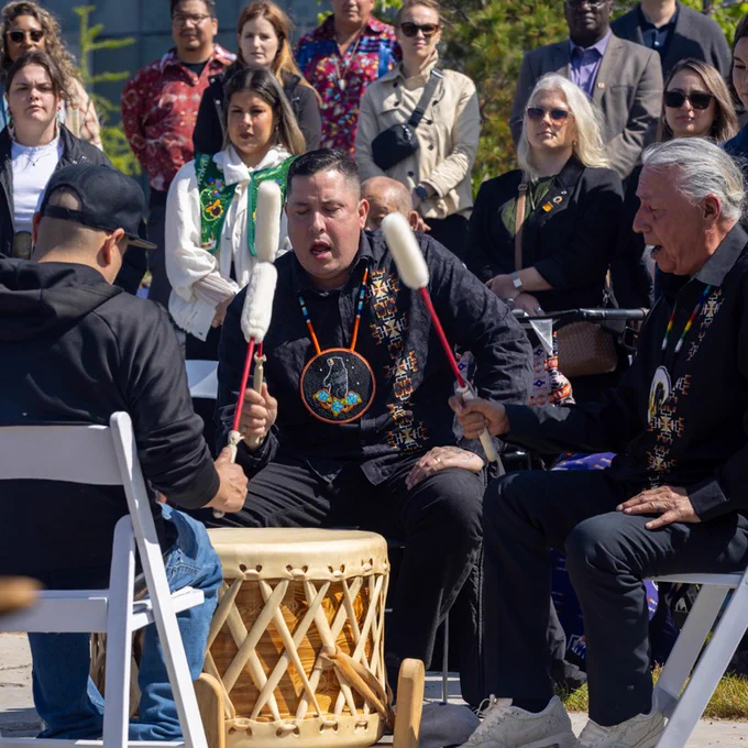 The ceremony included drummers in the Gathering Circle. They are surrounded by seated and standing attendees observing the performance.