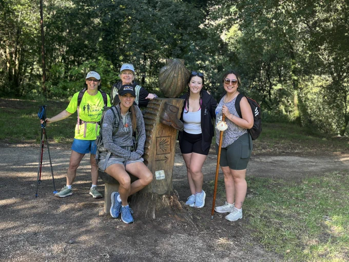Five pilgrims standing by a statue of boot and shell