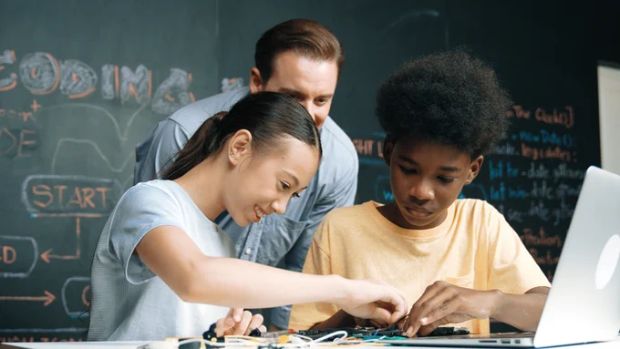 Teacher in classroom teaching middle school students robotics